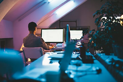 Young Caucasian programmer working on a computer code at his office at night.