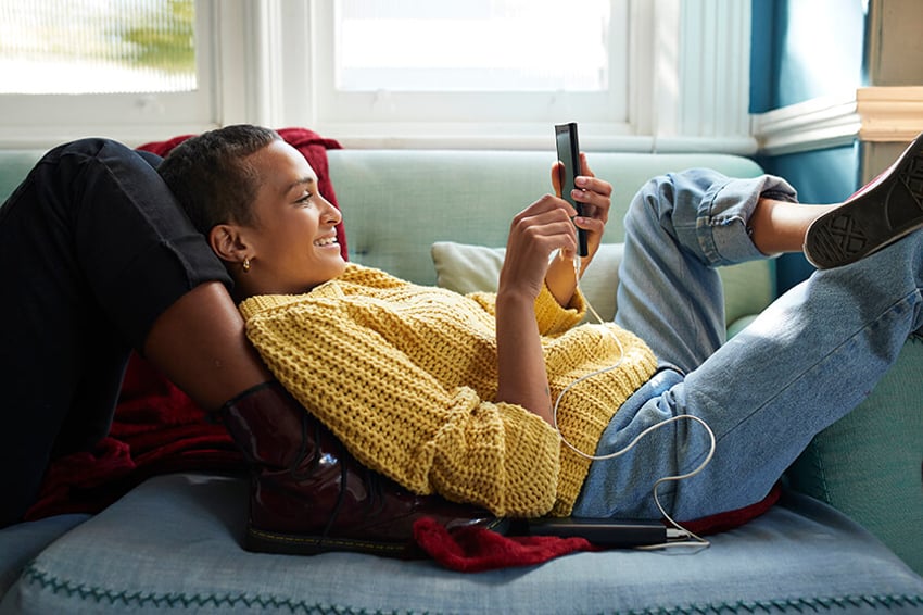 woman laying on couch looking at phone