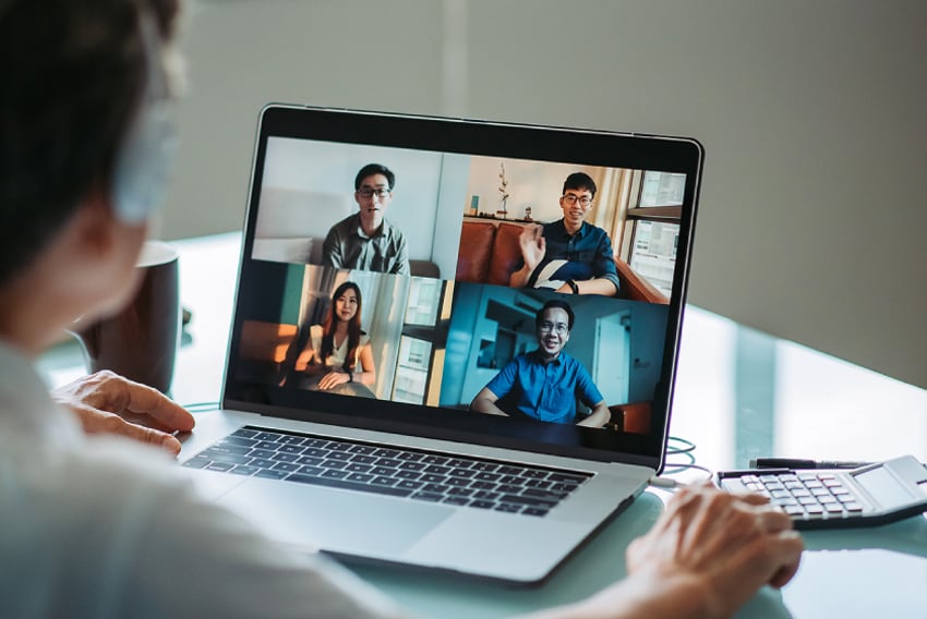 Video Conferencing header image Image of a laptop with a video call open on it and a person blurred out int the background engaging with the call