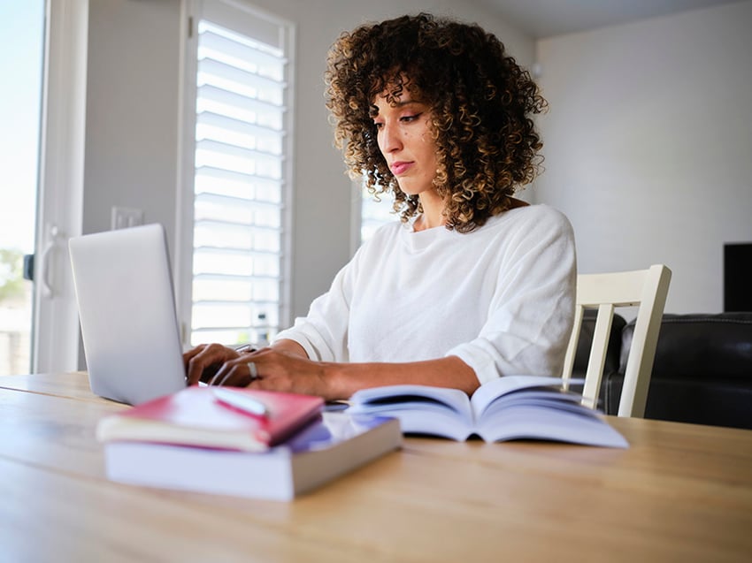 A young woman studying with a laptop computer in a home.