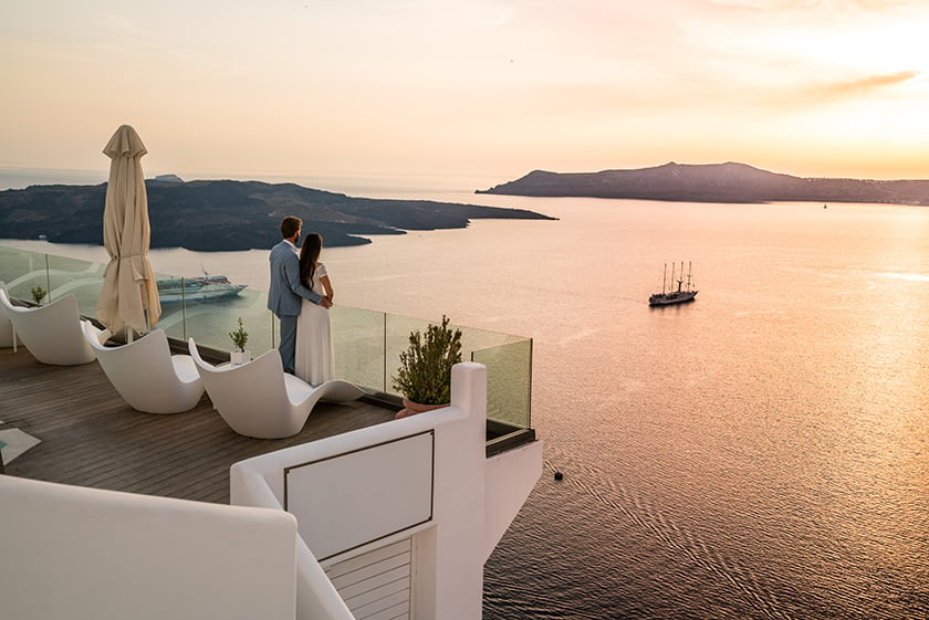 ギリシャの海を見下ろす高級ホテルで、ロマンティックな場所にたたずむカップル