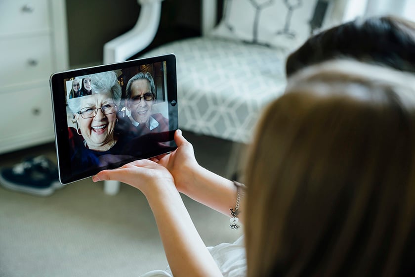 タブレット画面に映る祖父母と会話をする女性