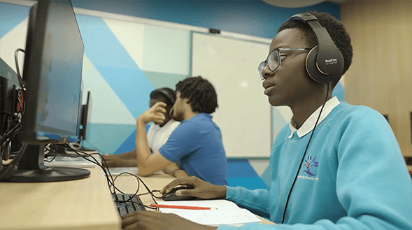 Image of child wearing headphones sitting at a computer